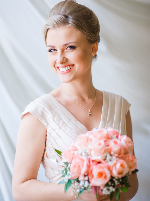 A radiant smiling bride carrying a bouquet